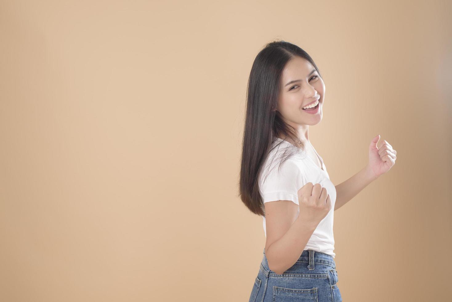 A Portrait of Asian woman with white T-shirt over Light brown background studio photo