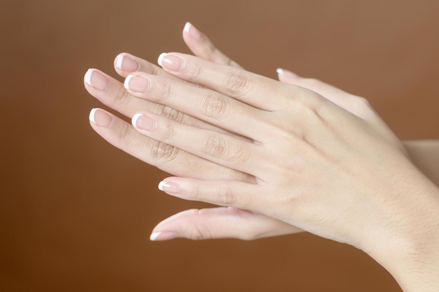 Close up young woman hand is applying cream over brown background , beauty skin care concept photo