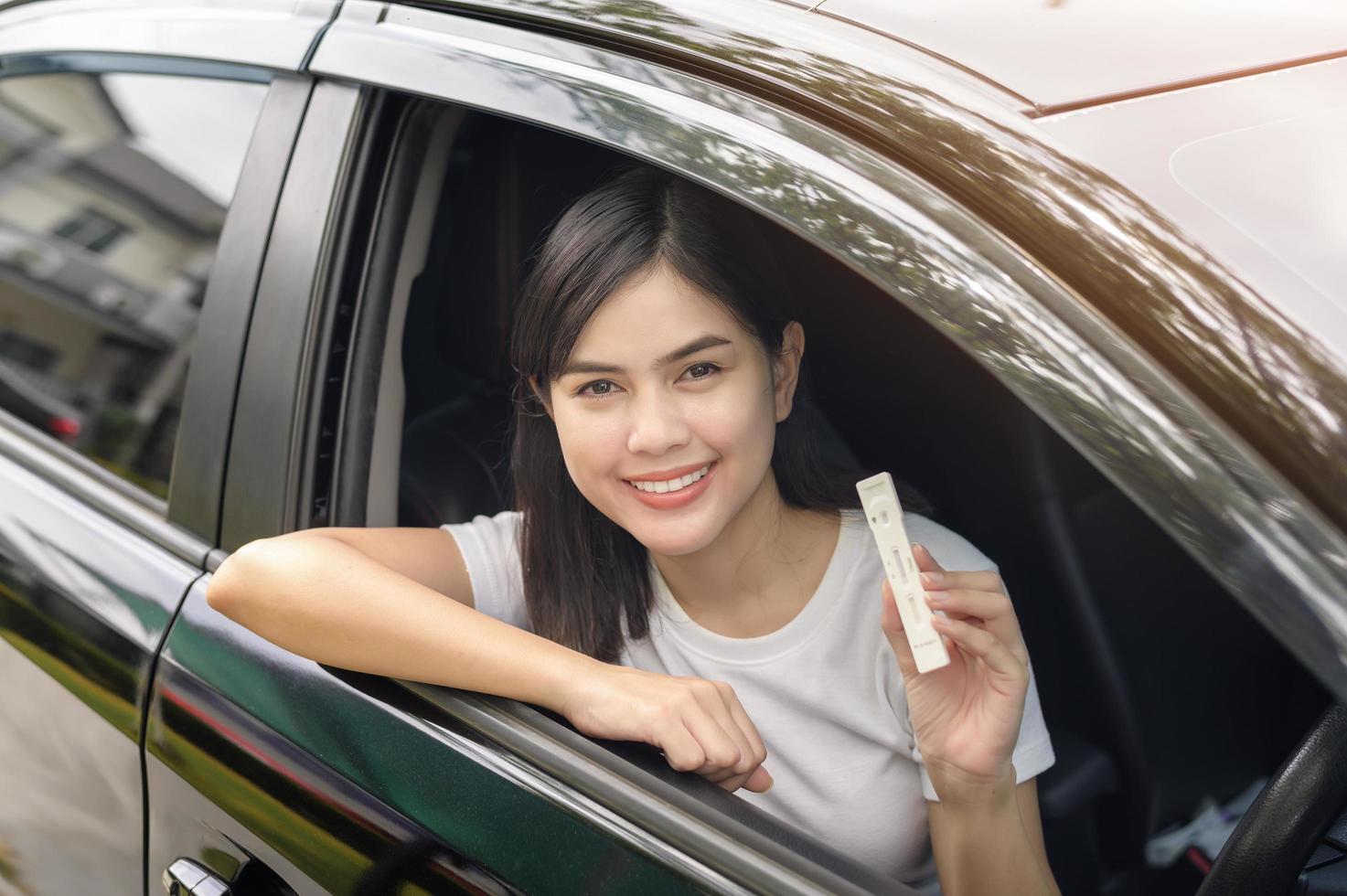 una mujer sosteniendo atk en el auto, haga una prueba de auto-recolección para una prueba covid-19, salud y seguridad foto