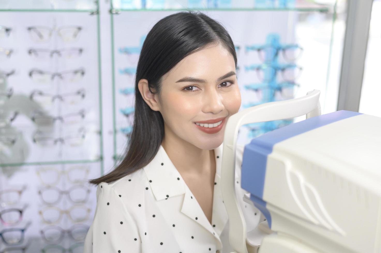 Young female customer being examined visual test using autorefractor by ophthalmologist in optical center, eyecare concept. photo