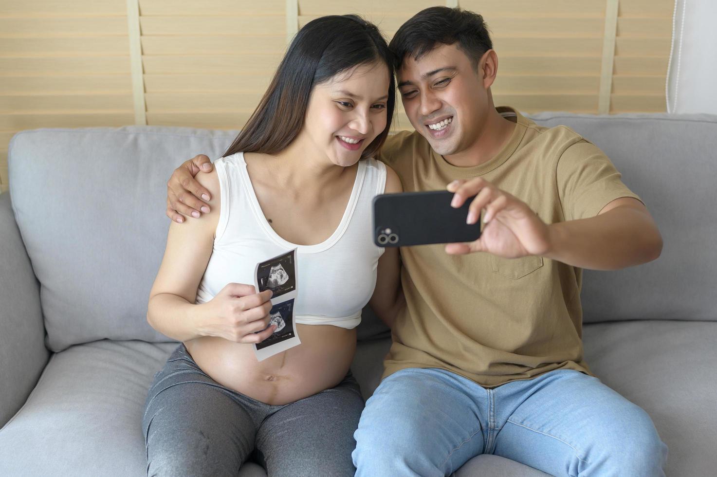 mujer embarazada joven con esposo abrazando y videollamada con familiares y amigos por teléfono inteligente en las redes sociales, concepto de atención familiar y de embarazo foto