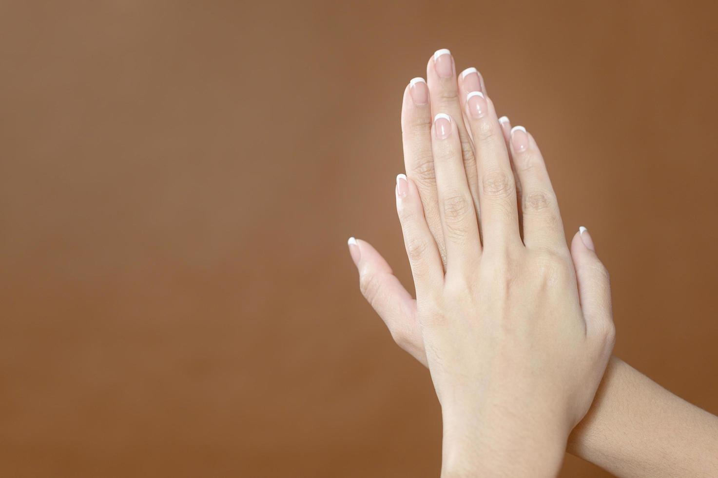 Close up young woman hand is applying cream over brown background , beauty skin care concept photo