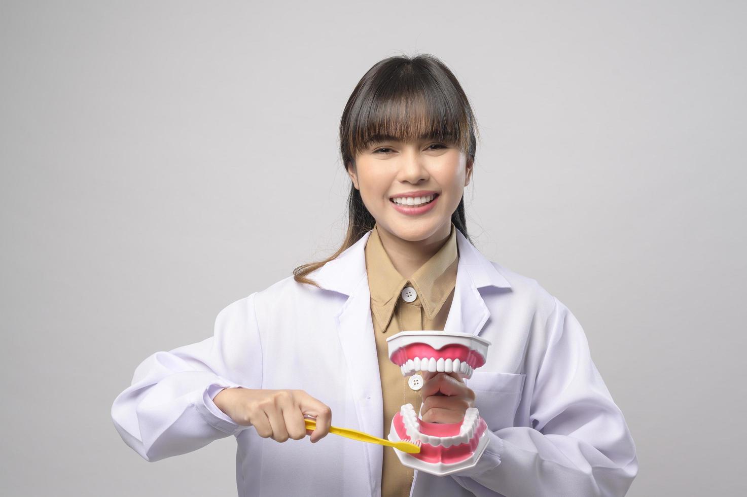 Una joven dentista sonriendo sobre un estudio de fondo blanco foto