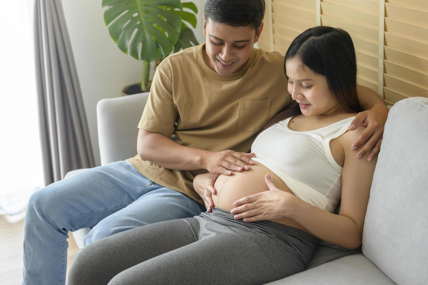 Young pregnant woman with husband embracing and expecting a baby at home photo