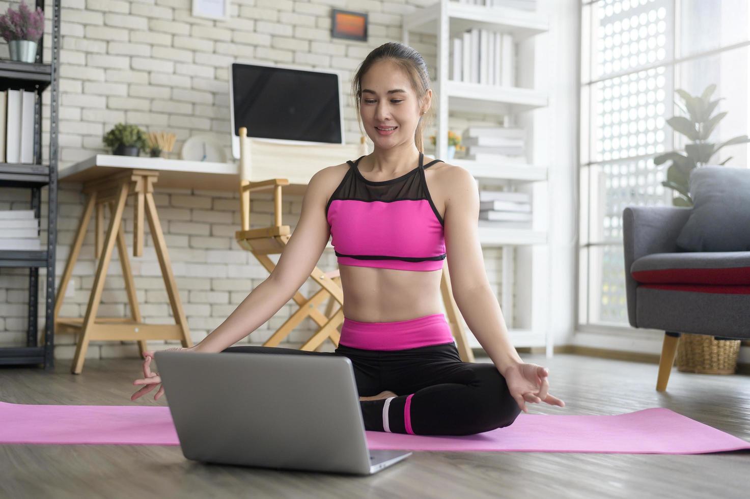 Fit young woman practicing yoga at home via online class with professional instructor, sport and healthy lifestyle concept. photo