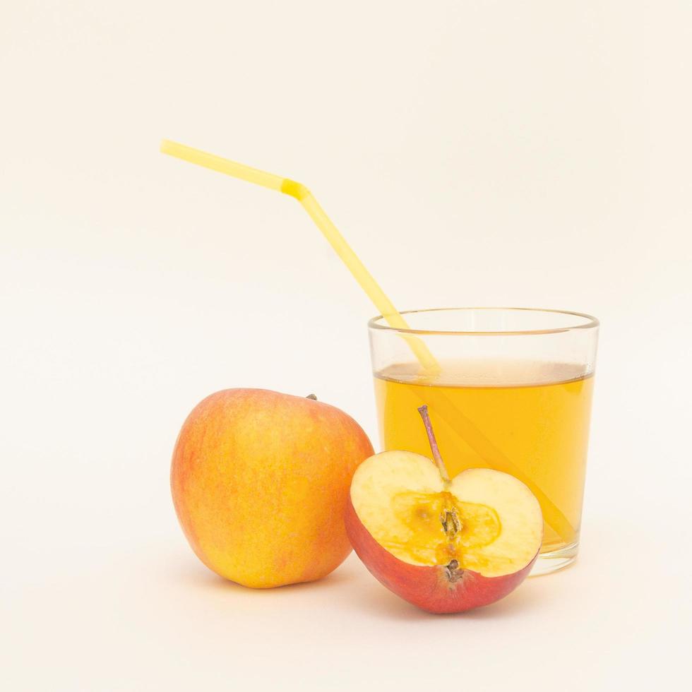 a glass of apple juice with straws and a little apples isolated on white background. photo