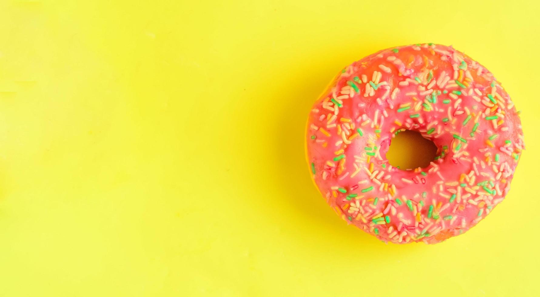 Pink donut on pastel yellow background. photo