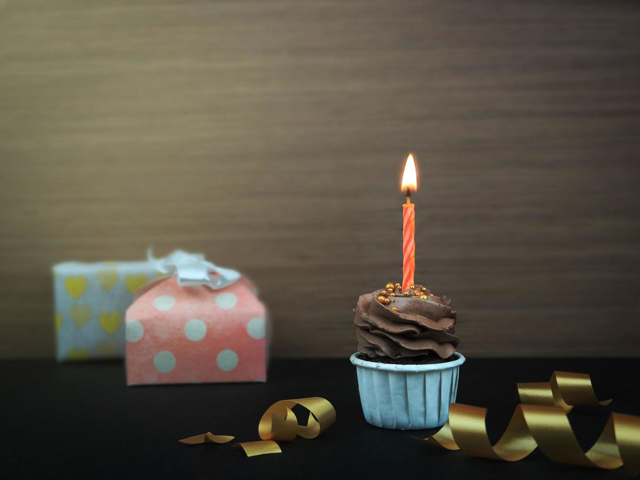 Sweet coffee chocolat cupcake with bow candle on wooden background with copy space. Happy birthday party background concept. photo