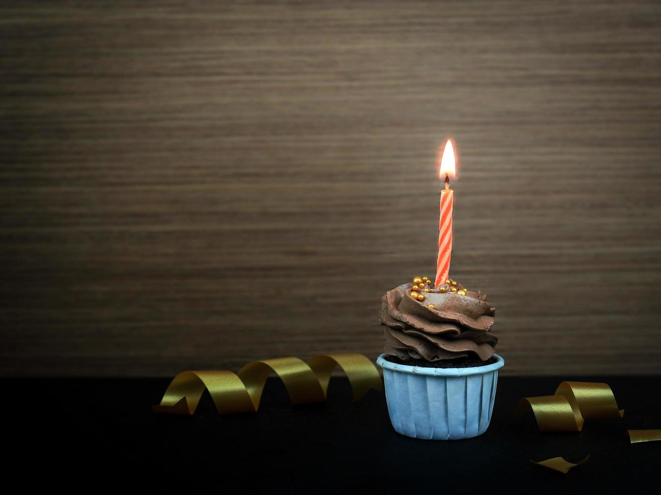 Sweet coffee chocolat cupcake with bow candle on wooden background with copy space. Happy birthday party background concept. photo