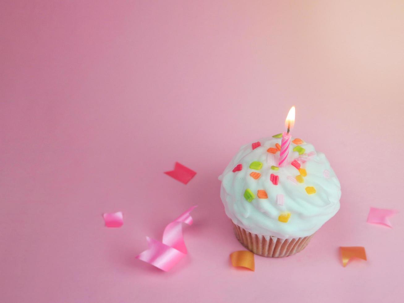 Happy birthday cupcake and bow candle on pink background with copy space. photo