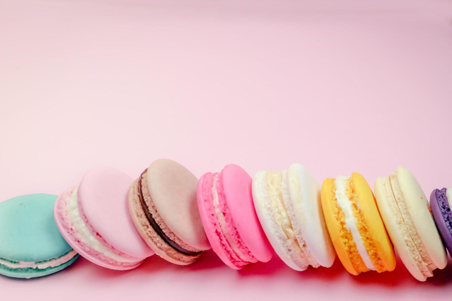 Colorful french macarons macaroons cake,  delicious sweet dessert on a pink background with copyspace, food background concept. photo