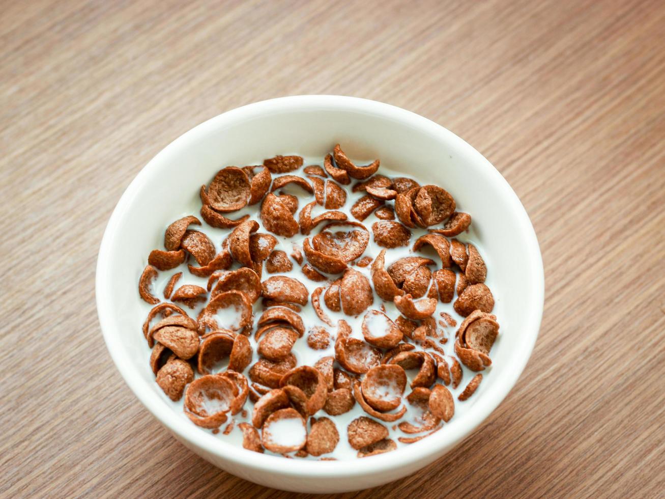 sabor a chocolate con cereales con leche en un tazón sobre una mesa de madera, desayuno listo para comer por la mañana foto