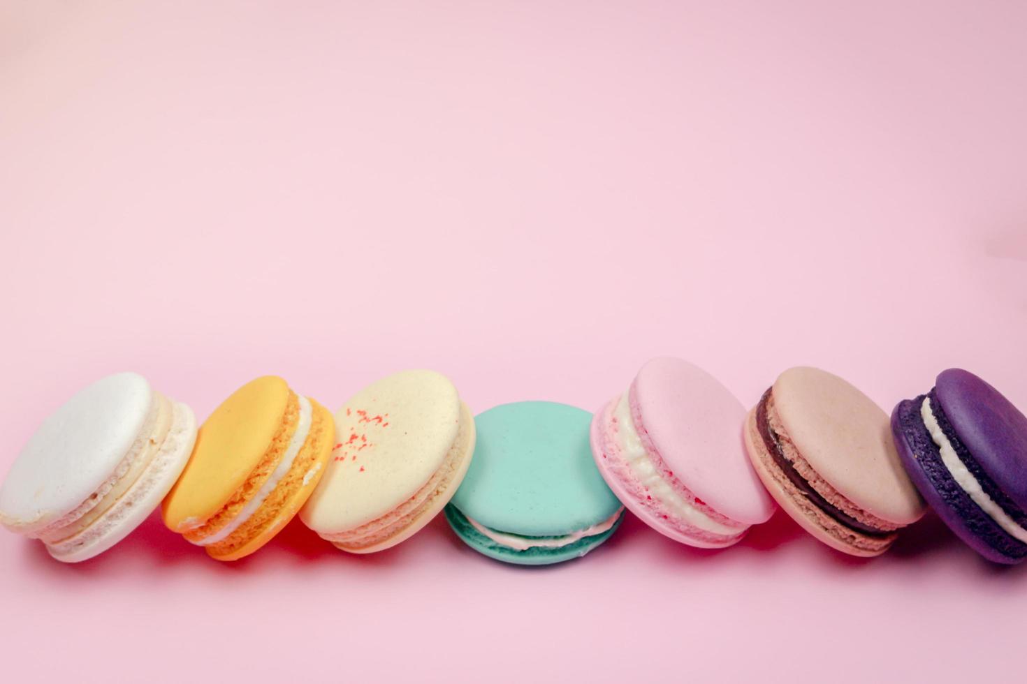 Colorful french macarons macaroons cake,  delicious sweet dessert on a pink background with copyspace, food background concept. photo