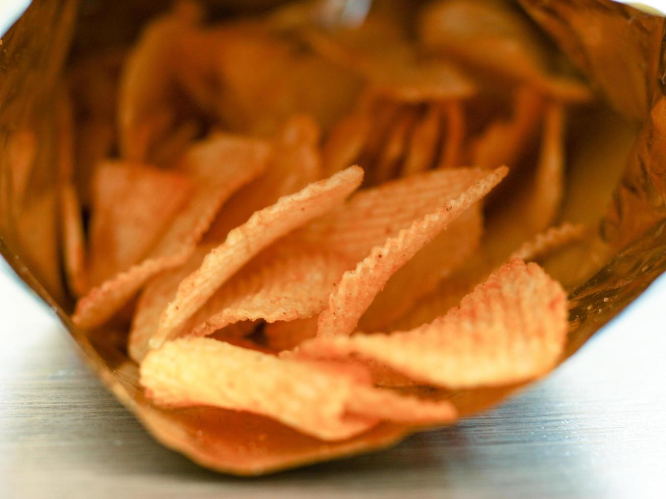 Potato chips in opened snack  bag, delicious junk food ready to eat. photo