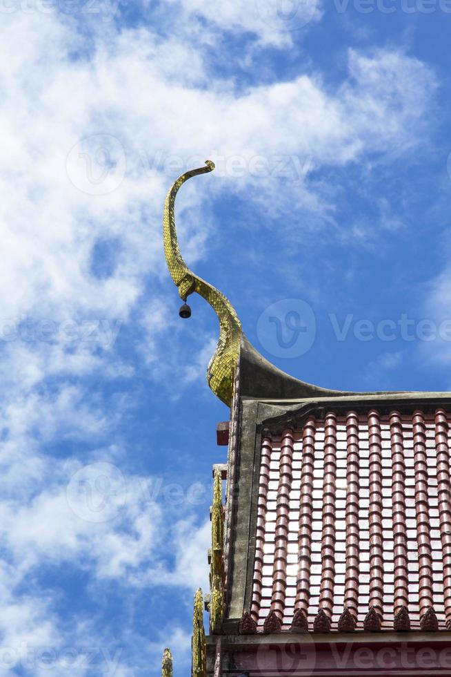 El techo rojo de un templo tailandés con ápice a dos aguas es un delicado arte tailandés creado por hábiles artesanos. y en todos los templos tailandeses es el mismo arte en el cielo azul en un día soleado. foto