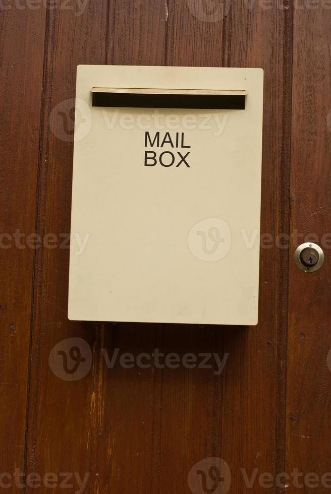 Ivory colour mailbox on the wooden door photo