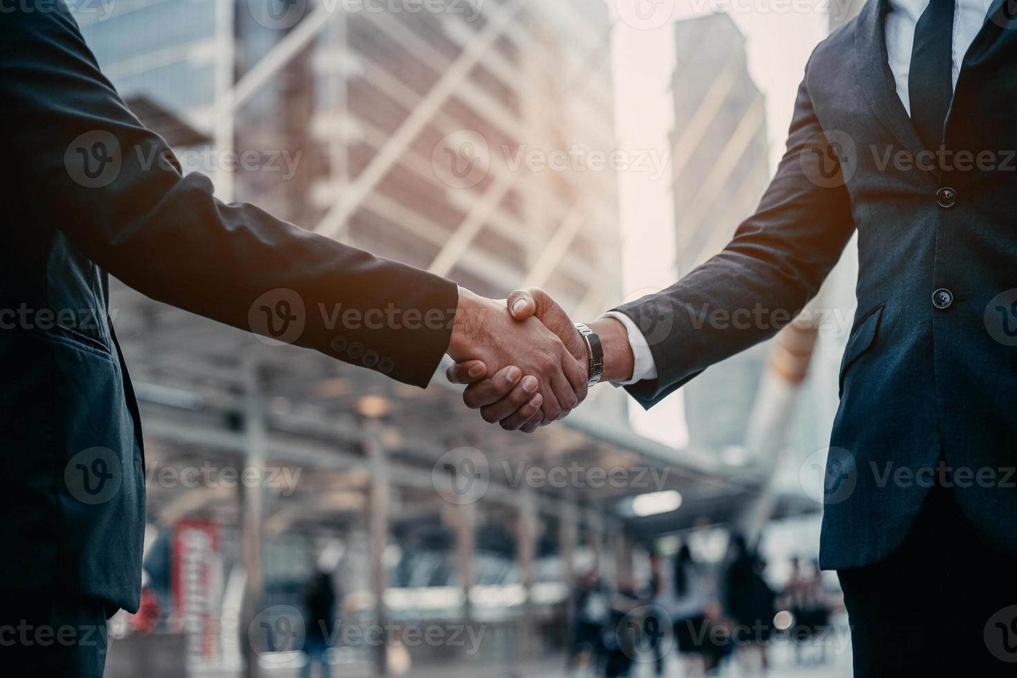 Businessman in suit handshake together for successful in city and walking people background. photo