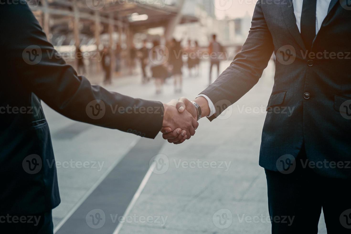 Businessman in suit handshake together for successful in city and walking people background. photo