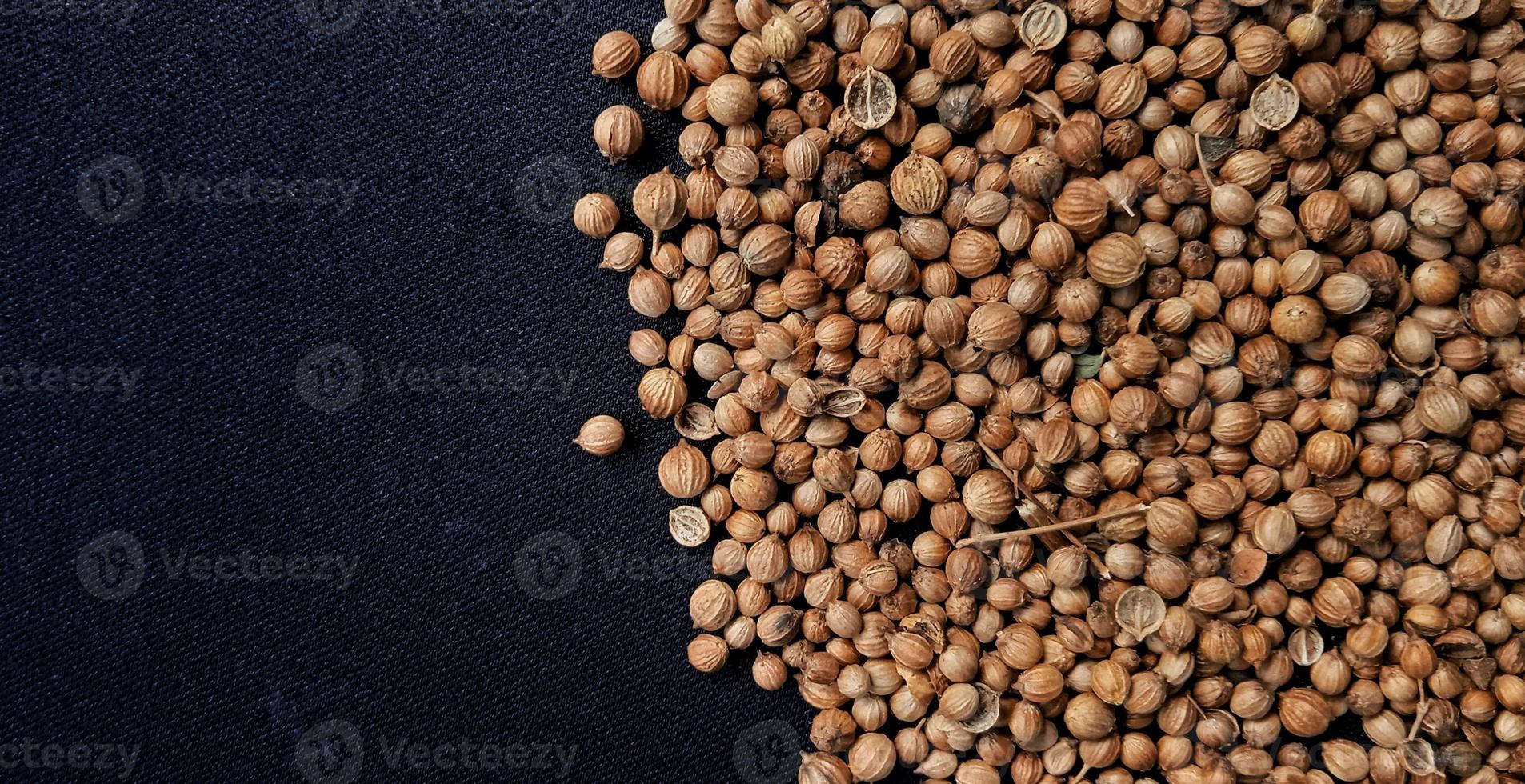 A spreaded dried coriander seed on black background. Ingredient background design. Available for text. Suitable for the food advertising of company and industry, poster, backdrop, flyer, etc. photo