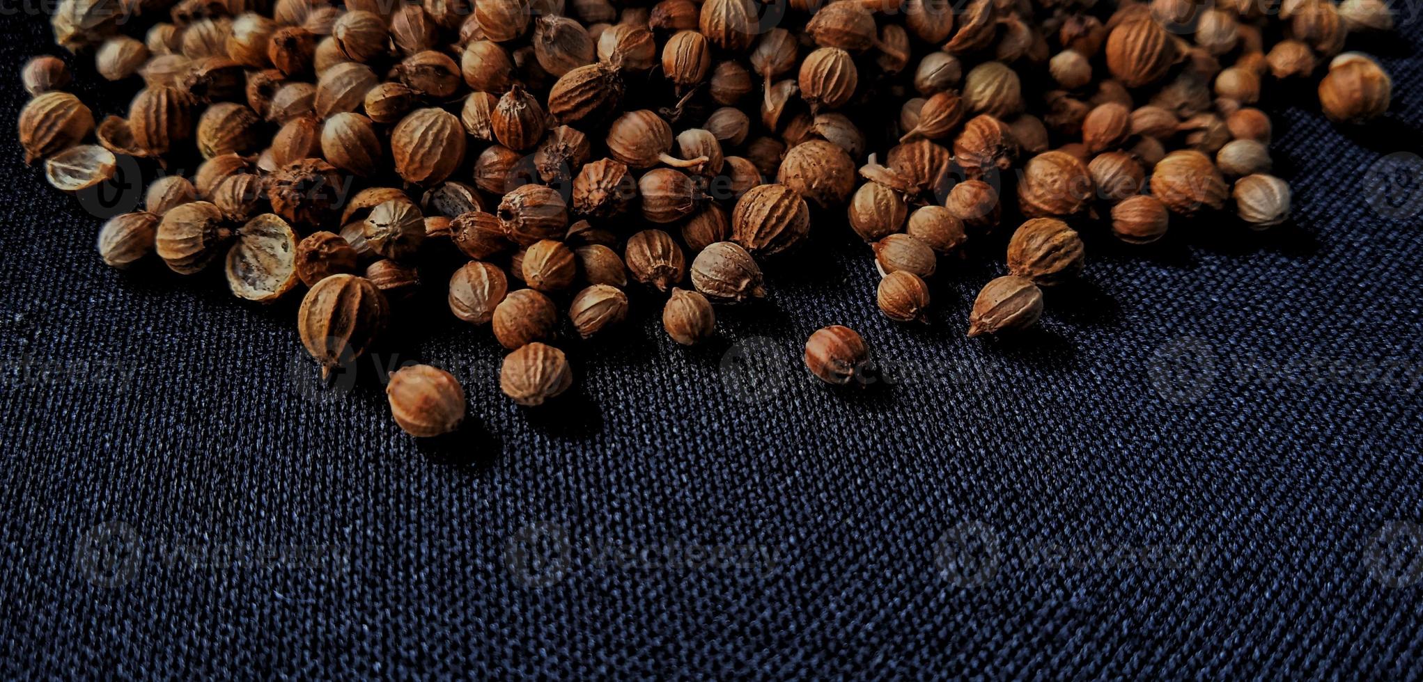A spreaded dried coriander seed on black background. Ingredient background design. Available for text. Suitable for the food advertising of company and industry, poster, backdrop, flyer, etc. photo