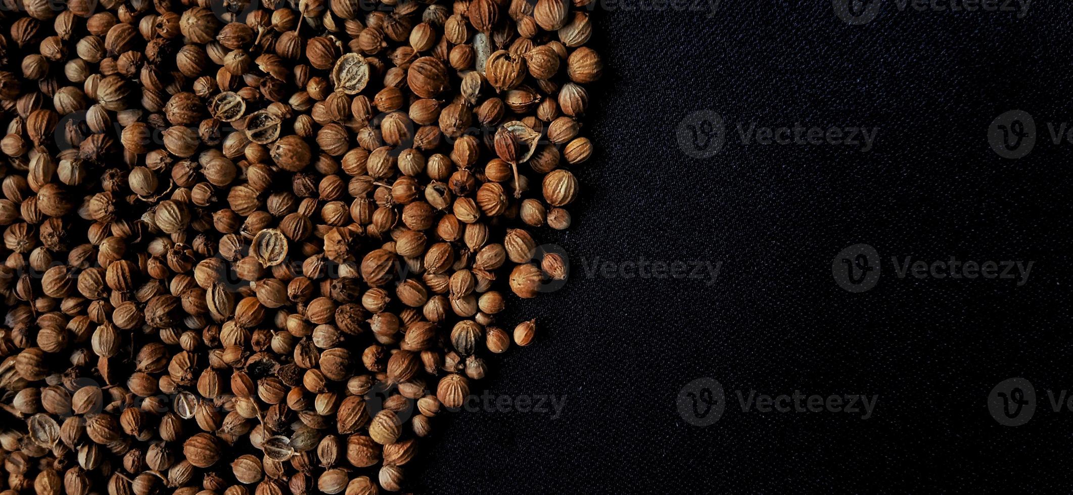 A spreaded dried coriander seed on black background. Ingredient background design. Available for text. Suitable for the food advertising of company and industry, poster, backdrop, flyer, etc. photo