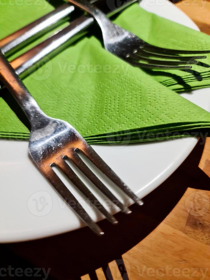 cubiertos de plata en un plato blanco con servilleta verde - enfoque selectivo foto