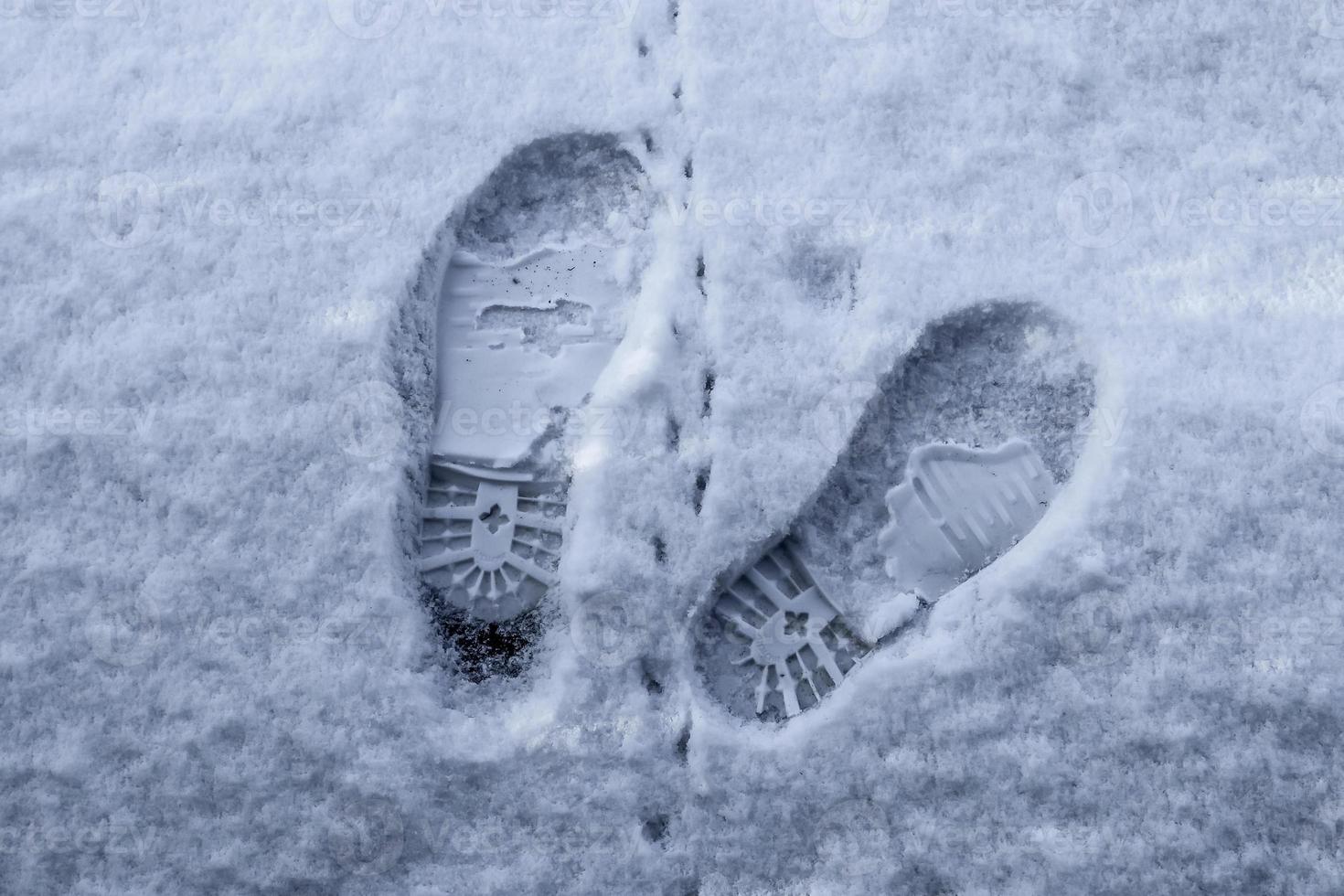 Footsteps of male shoes in fresh white snow in winter photo