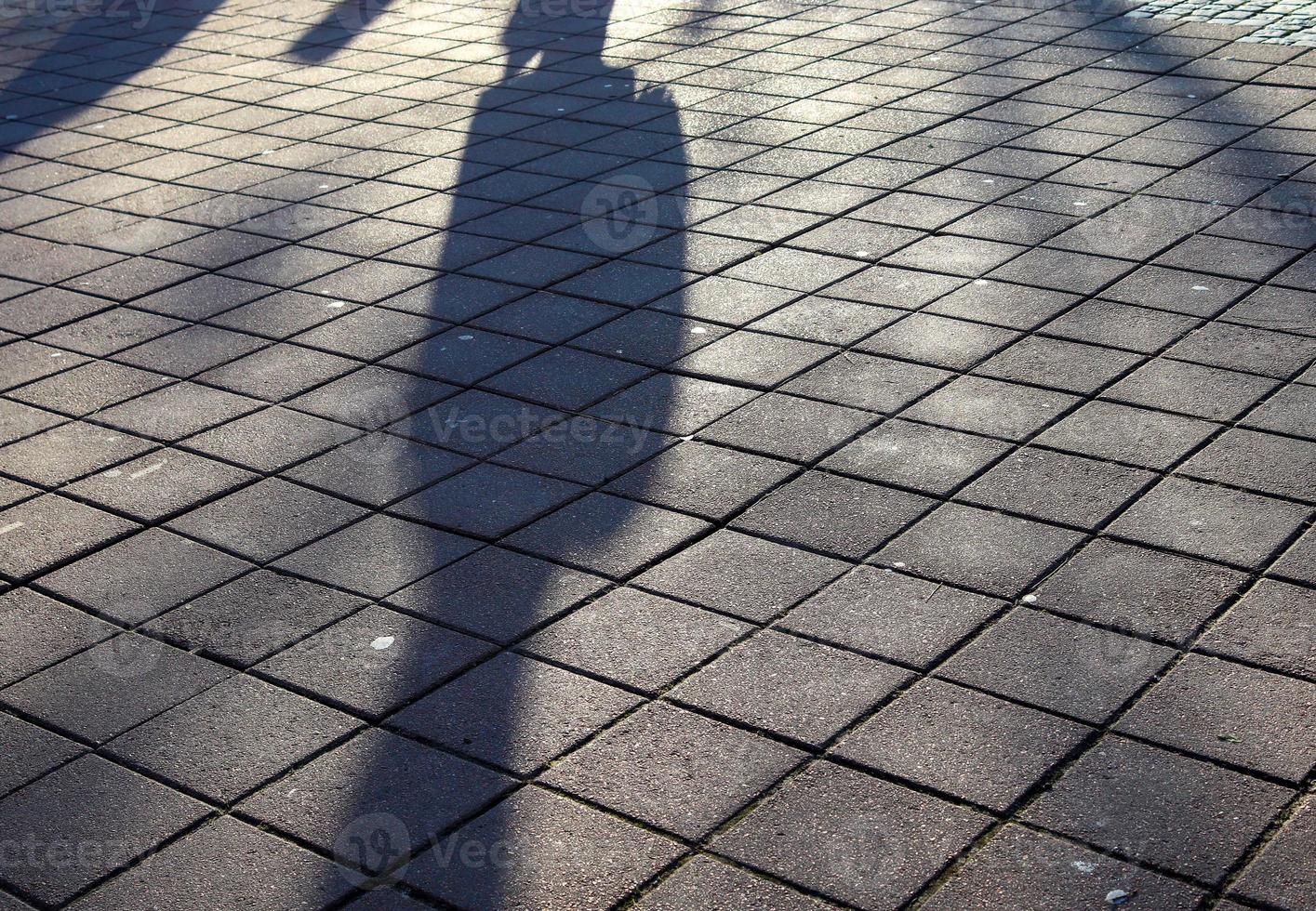 Shadows of people in a european shopping area on a cobblestone ground photo