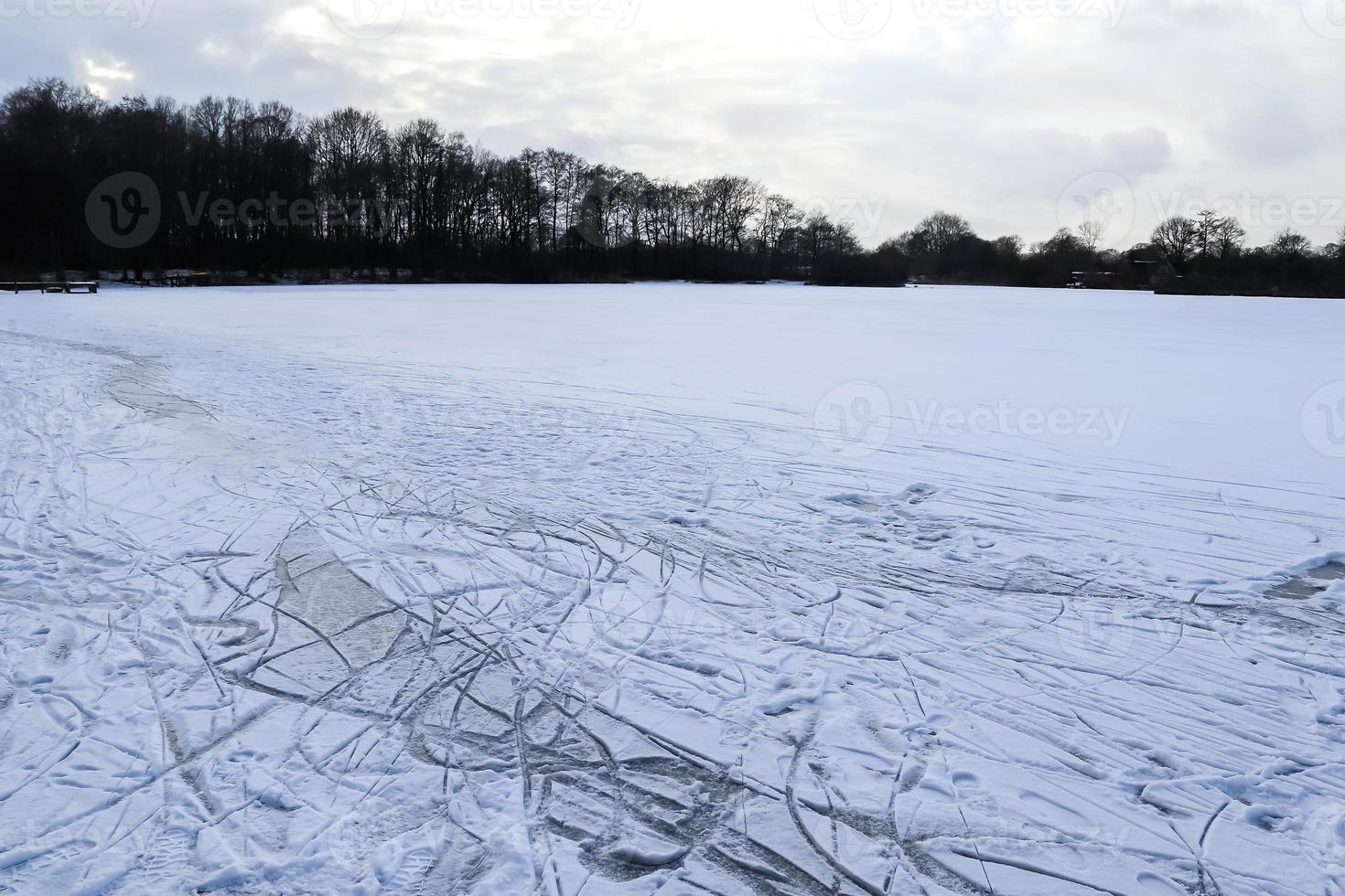 ver en un lago congelado durante el invierno con un montón de pistas de patinaje sobre hielo. foto