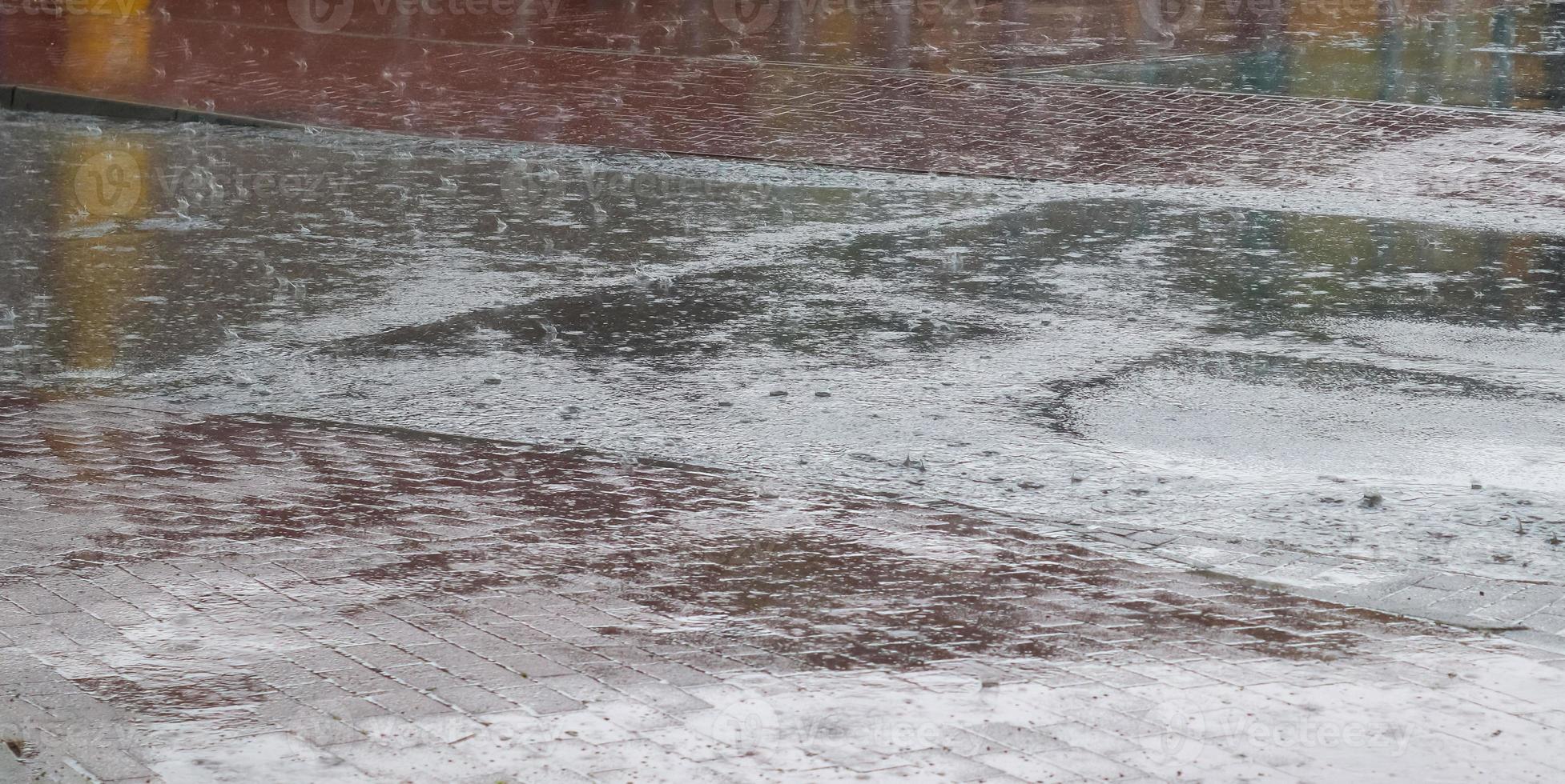 Wet ashpalt road texture. Heavy rain drops falling on city street during downpour. photo