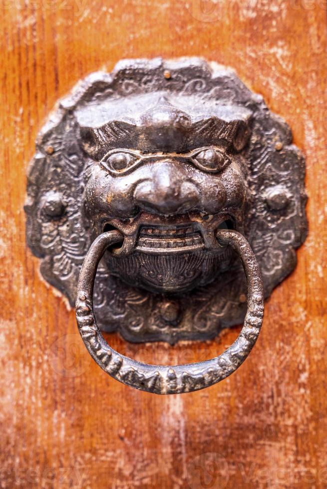 Detail of old metallic knocker or handle on the wooden door photo