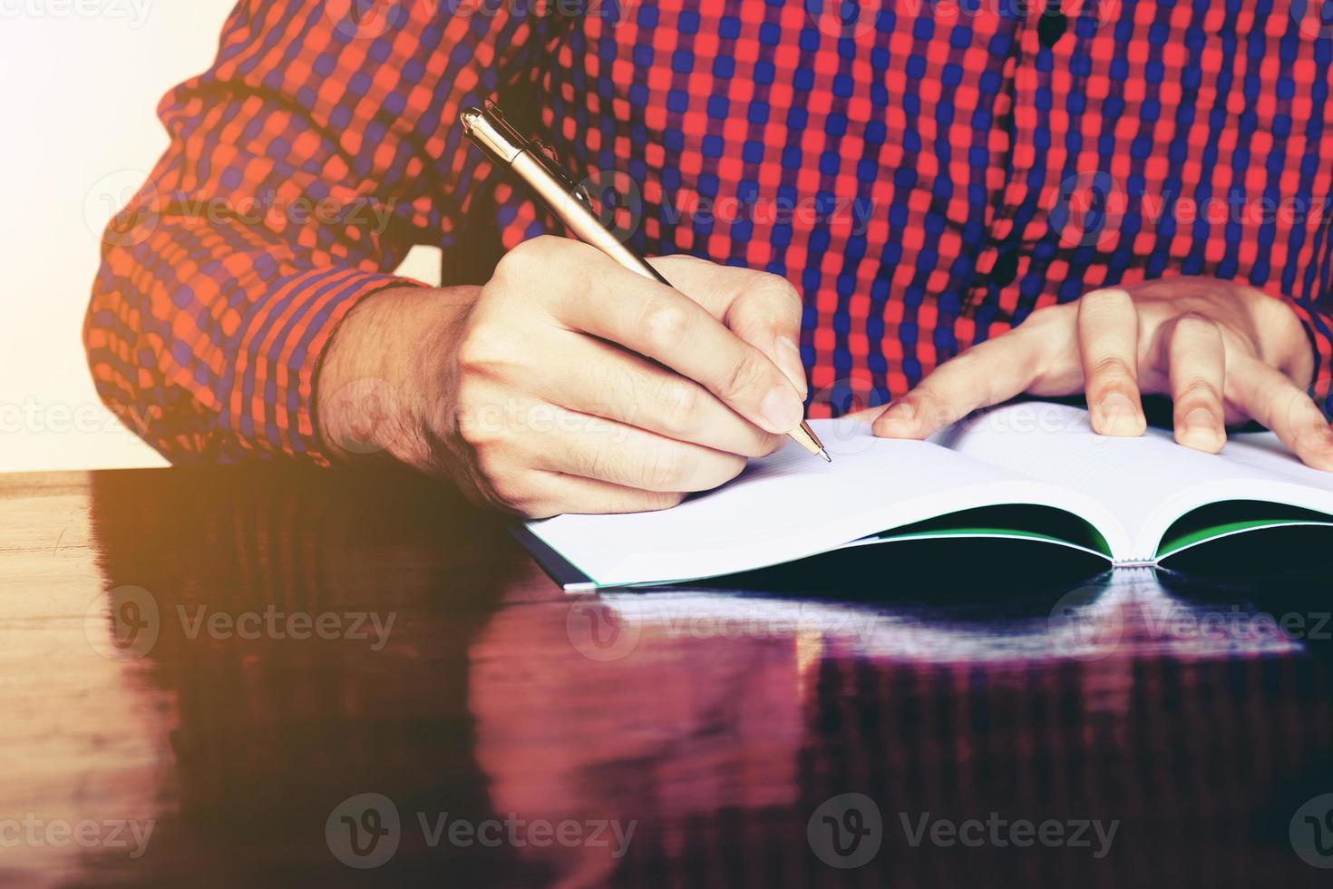 Young man hand writing on notebook with pen. photo