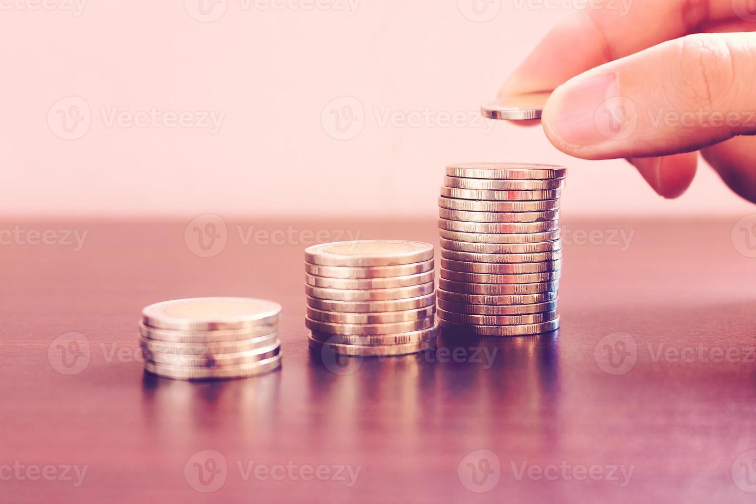 Ahorre el concepto de dinero con el hombre de la mano poniendo monedas en el juego de pilas. foto