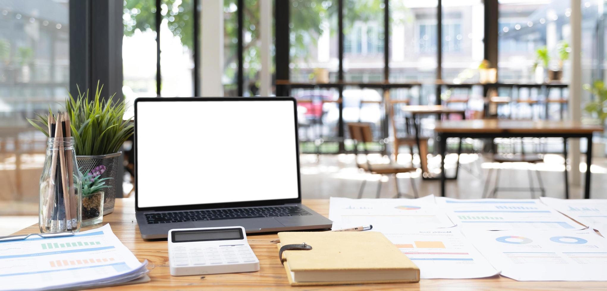 Laptop or notebook with blank screen on wood table in blurry background with house or office modern ,nature orange bokeh and sunlight in morning. photo