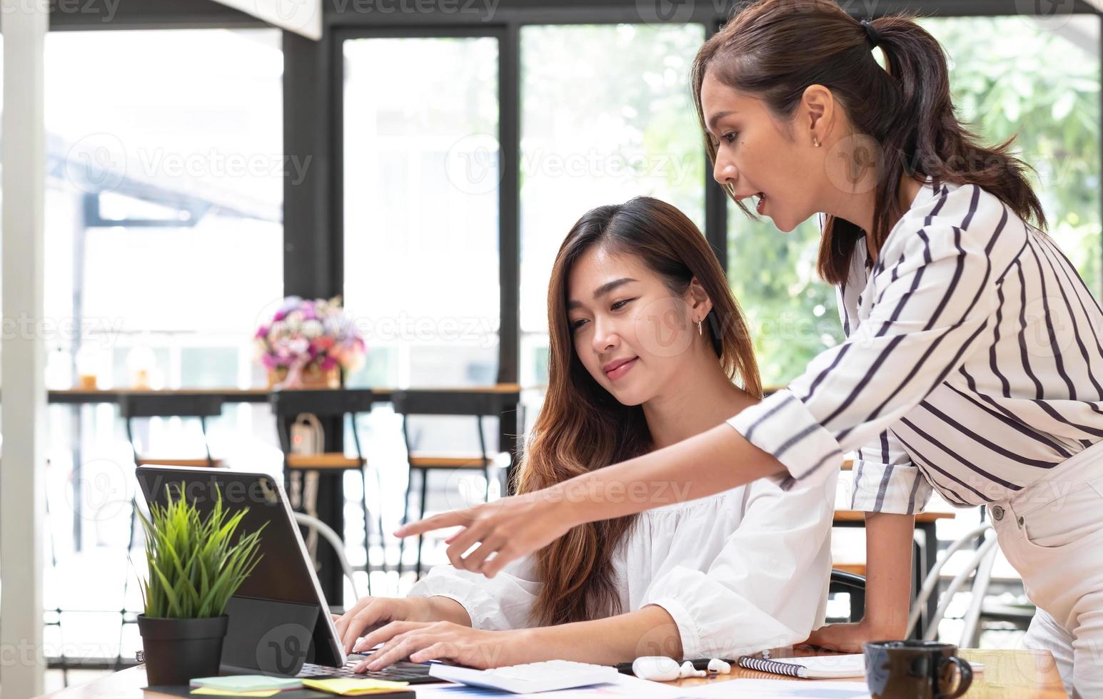 Two young beautiful asian business woman in the conversation, exchanging ideas at work. photo