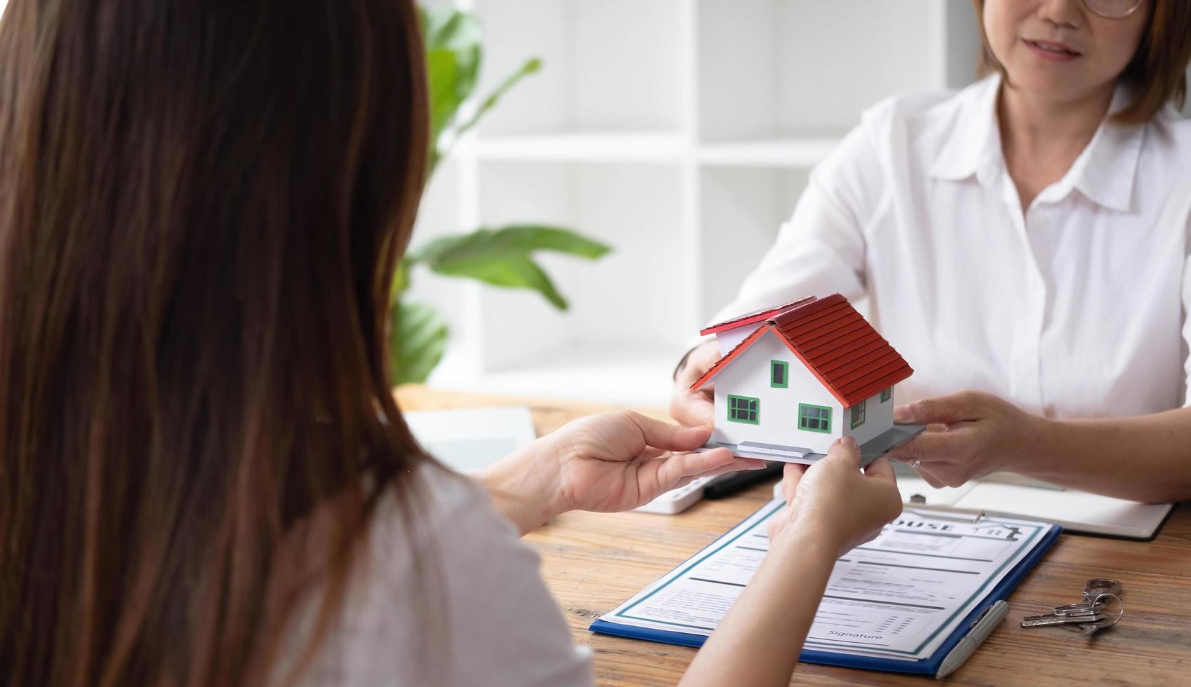 A real estate broker or insurance agent works with home models and home real estate sales contracts within the office, Mortgage loan approval home loan and insurance concept. photo