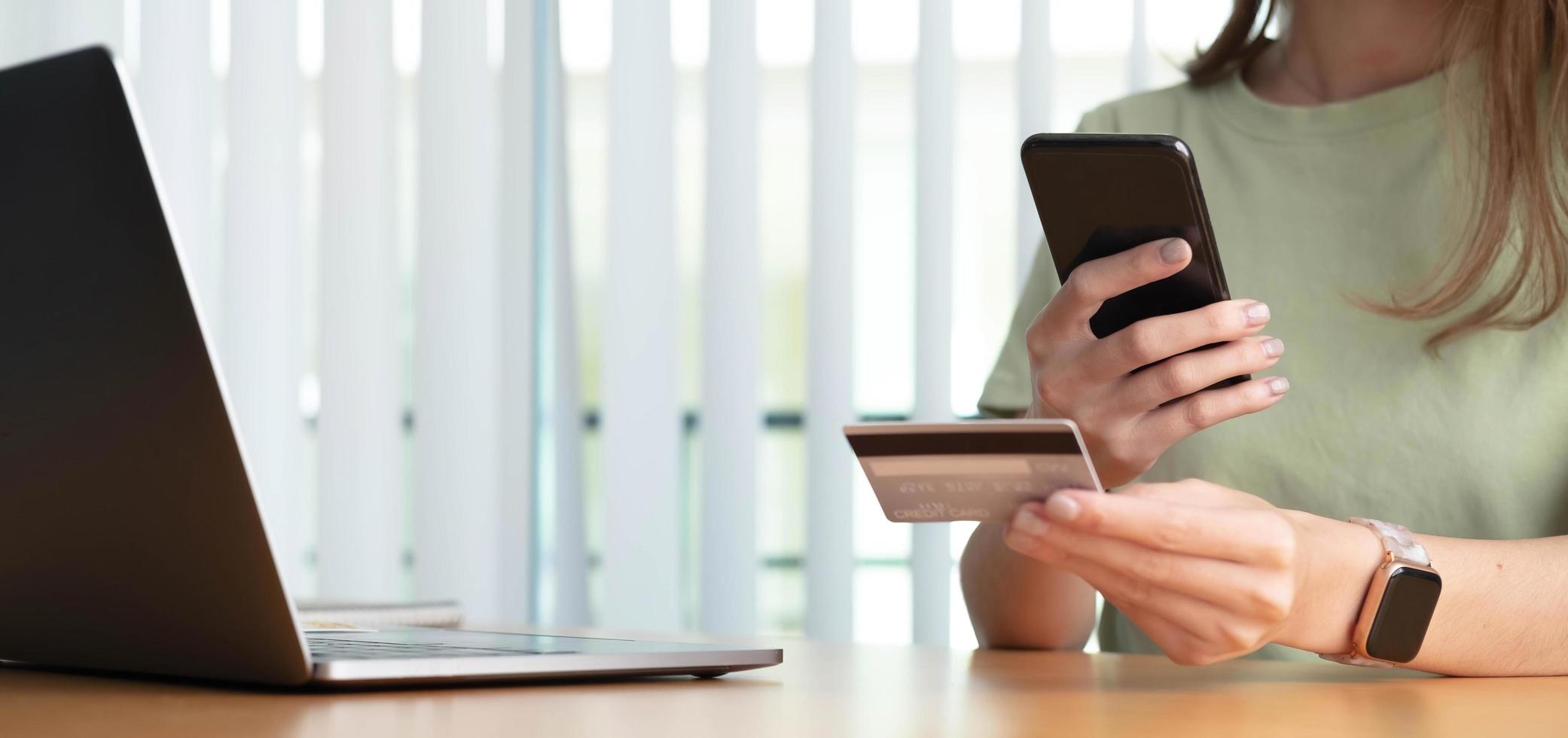 Close up female hands holding credit card and smartphone, young woman paying online, using banking service, entering information, shopping, ordering in internet store, doing secure payment photo