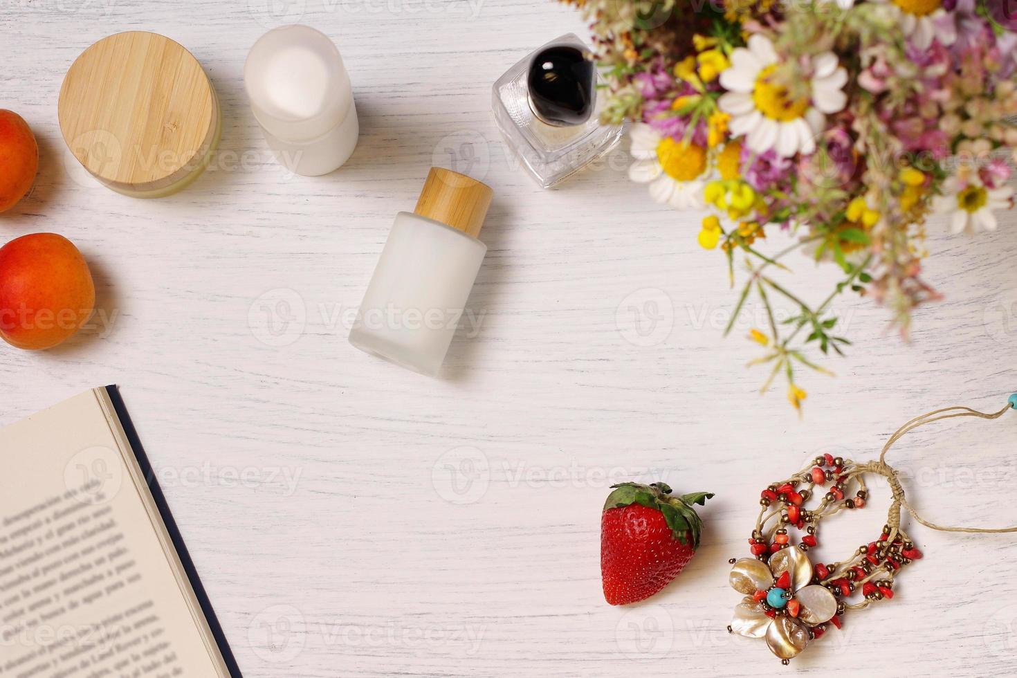 Cosmetic bottles, fruit flowers and book on table, lifestyle staging photo