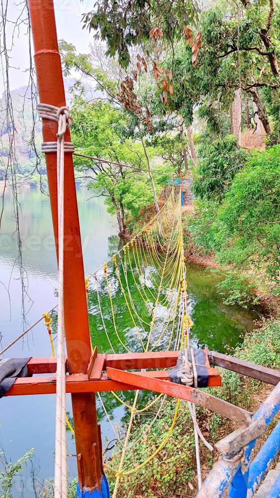 A rope bridge is suspended over a river in Uttarakhand, India. photo