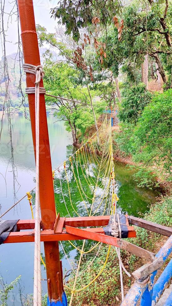 un puente de cuerda está suspendido sobre un río en uttarakhand, india. foto