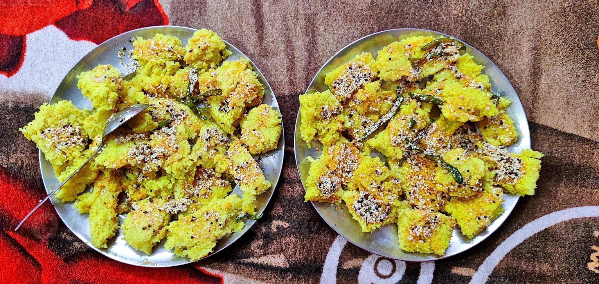 el popular plato indio dhokla se coloca en placas de metal adornadas con semillas de mostaza frita, chile verde y sésamo. foto