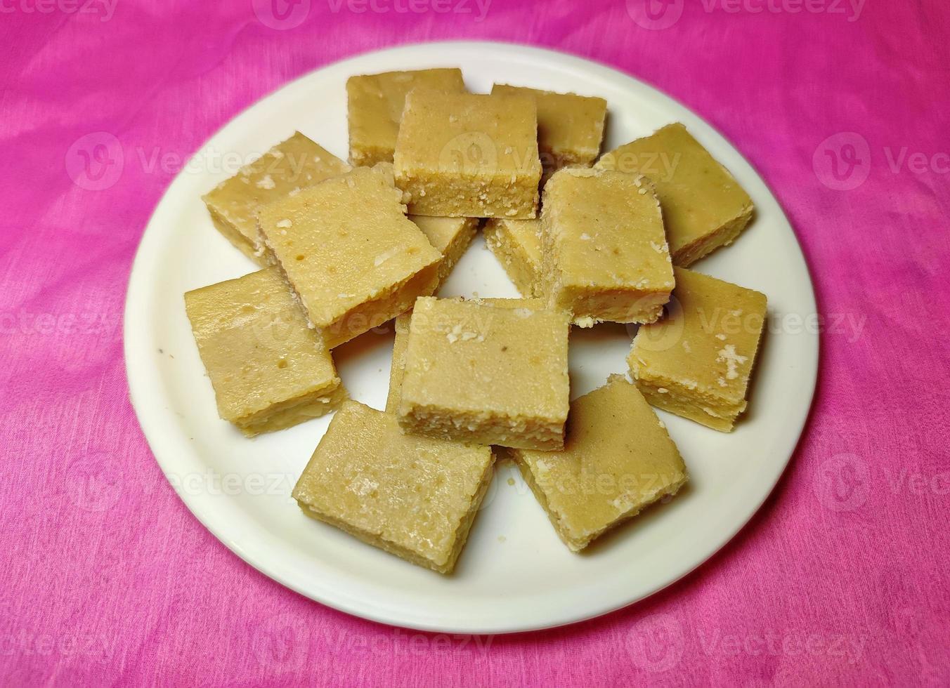 Mawa Burfi - a delicious Indian festival sweet on a white plate on a coloured background. photo