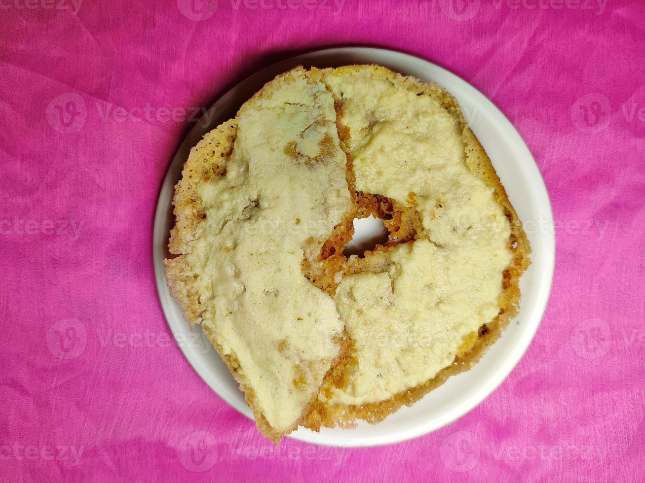 Ghevar - a traditional Indian Disc-shaped festival sweet, placed on a white plate on coloured background photo