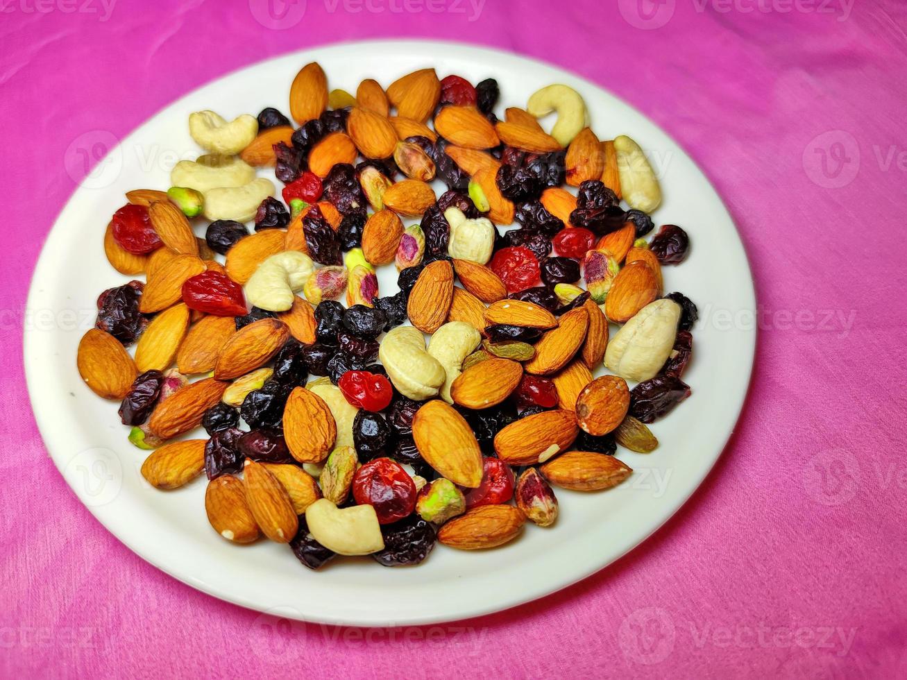 Healthy and nutritious Nuts and Berries are placed on a white plate on a coloured background. photo