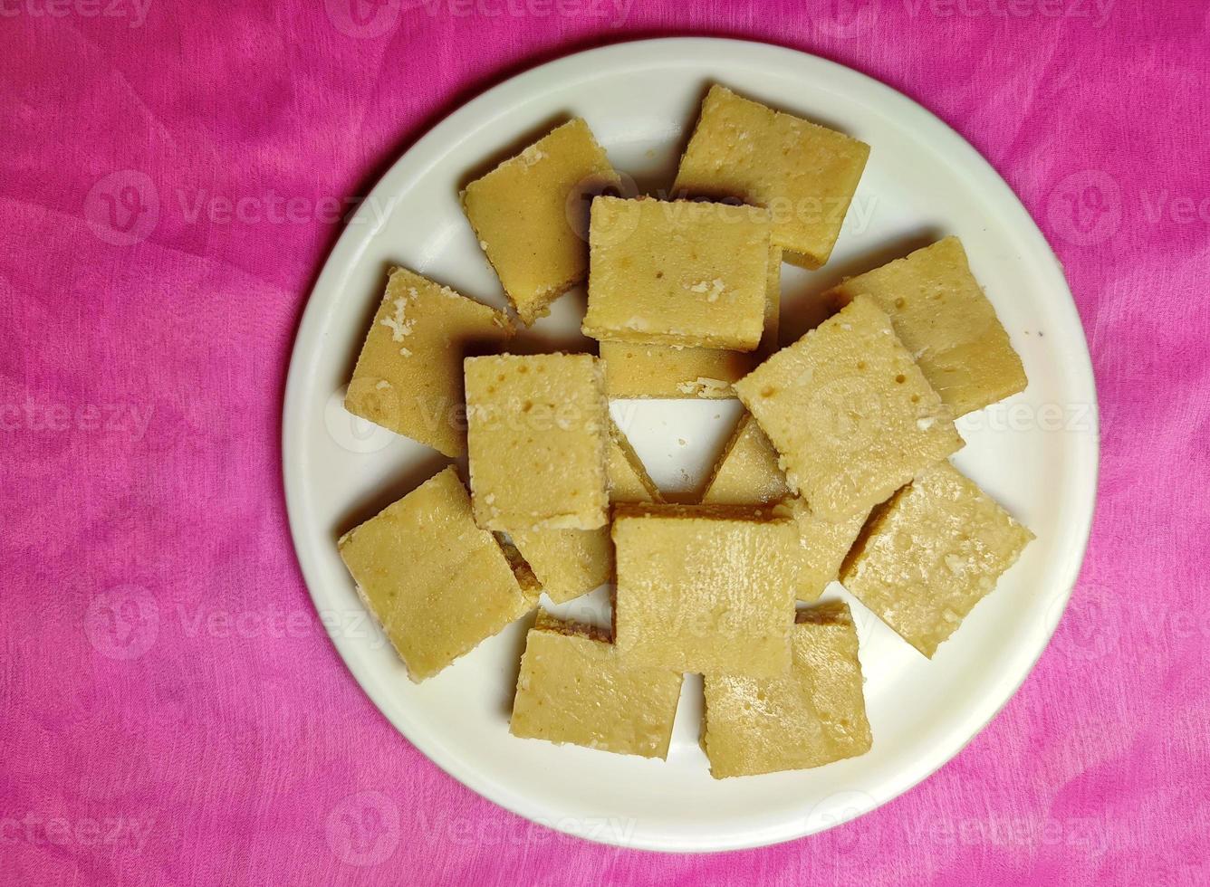Mawa Burfi - a delicious Indian festival sweet on a white plate on a coloured background. photo