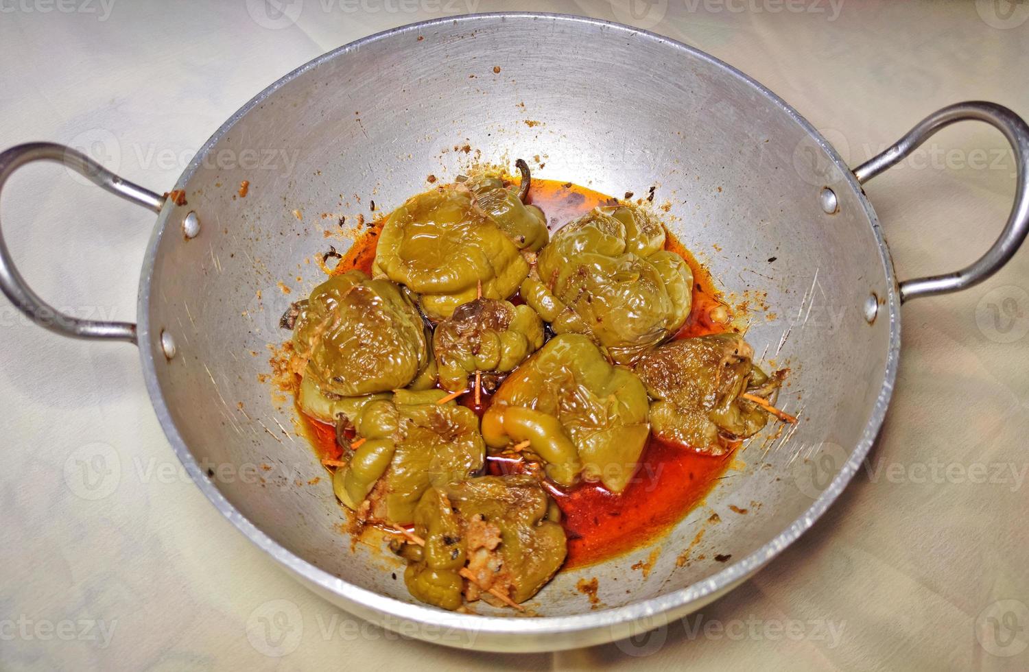 Boiled and spicy potatoes stuffed Shimla Mirch ki Sabzi - stuffed spicy capsicum curry - placed on a silver coloured wok. photo