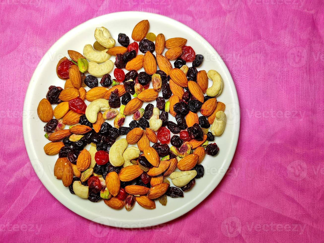 Healthy and nutritious Nuts and Berries are placed on a white plate on a coloured background. photo