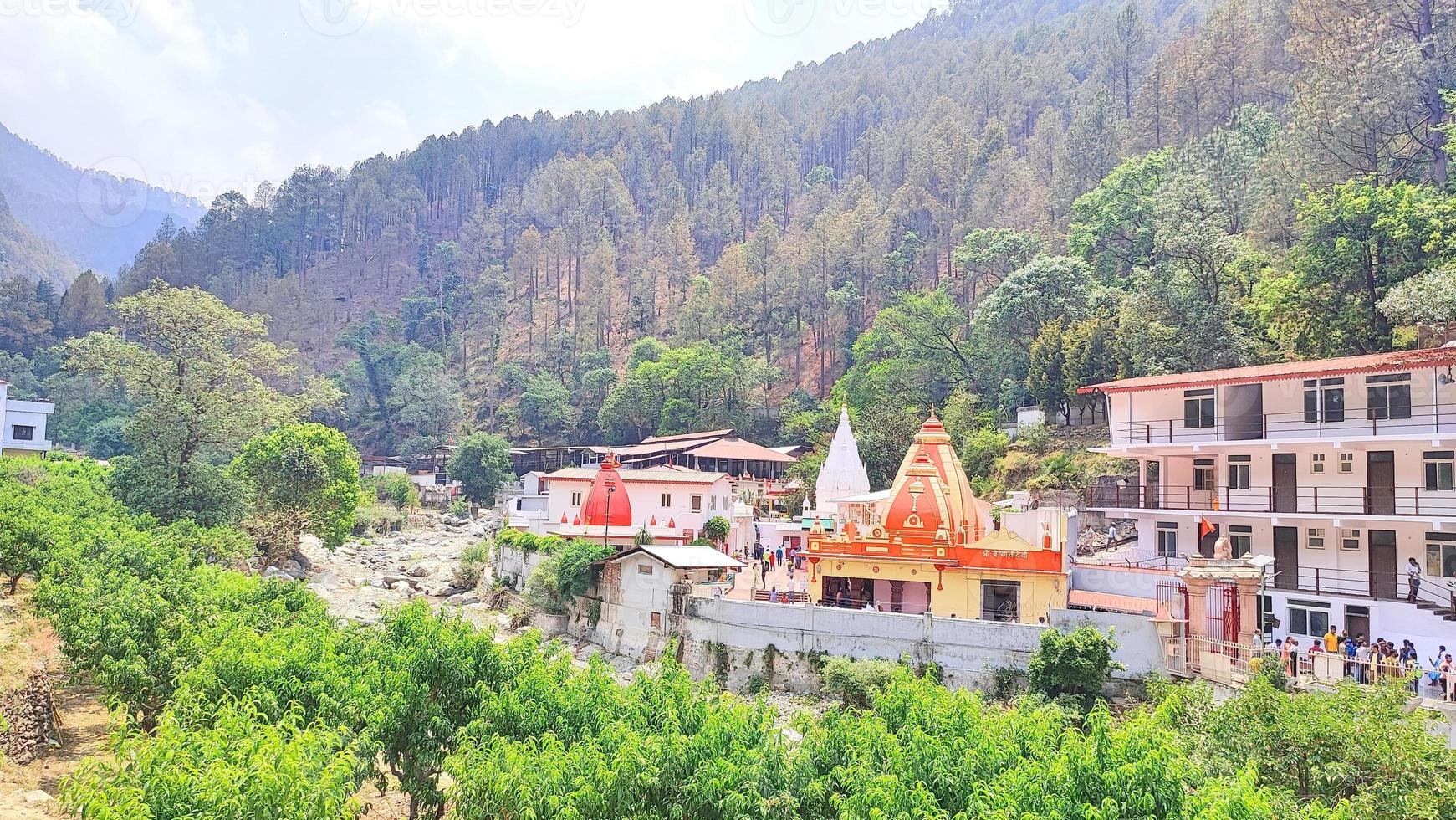 Kainchi Dham Uttarakhand holy temple is surrounded by hills and trees and a river flowing beside it. photo