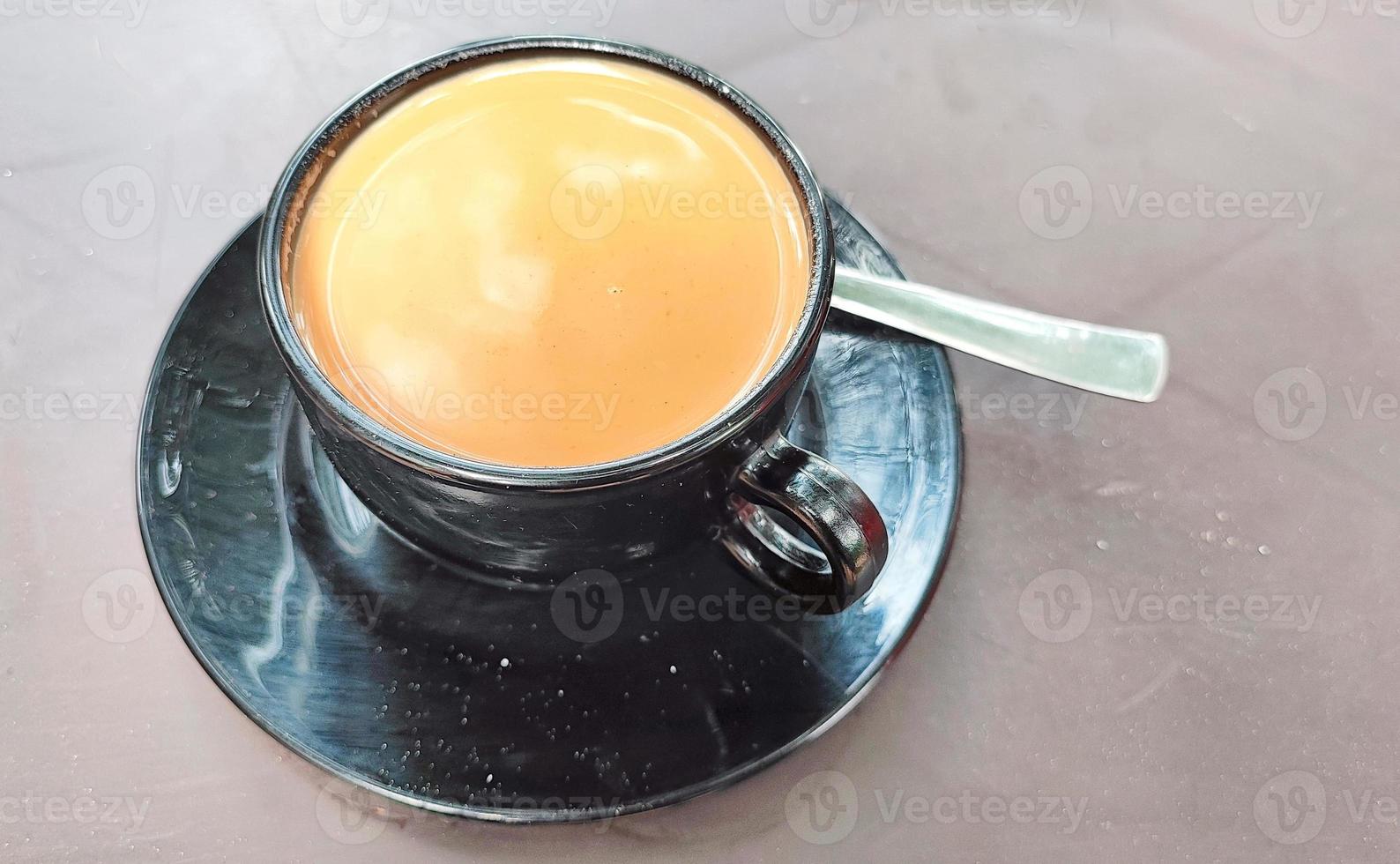 té de azúcar en un plato de taza negra sobre fondo marrón foto