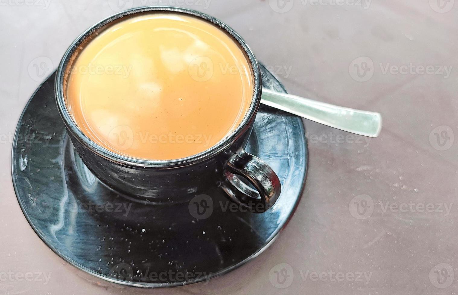 té de azúcar en un plato de taza negra sobre fondo marrón foto